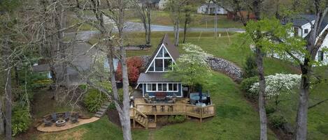 A house with a deck, a hot tub, and a fire pit in the yard.