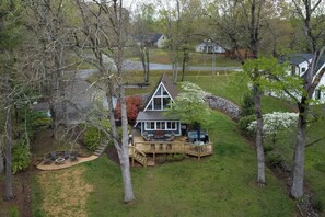 A house with a deck, a hot tub, and a fire pit in the yard.