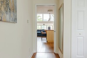 Un couloir mène à un espace de vie comprenant une cuisine, une table à manger et un coin bar.
