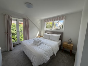 Une chambre à coucher avec un lit, une fenêtre, une table de chevet et une vue sur la verdure.