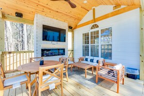 A wooden deck with a brick fireplace, outdoor seating, and a TV mounted on the wall. - Luxury Atlanta Home(6 Bedrooms) (Atlanta)