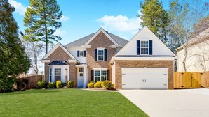 A two-story house with a brick facade, a white garage door, and a well-maintained lawn.