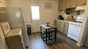 Eine kleine Küche mit Kühlschrank, Mikrowelle, Herd und Holzböden.