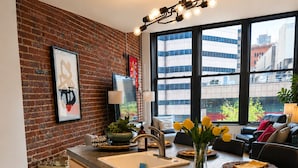 A modern kitchen with a brick wall, a large window, and a dining area with a view of buildings. - NEW LISTING Charming 2/2 loft/heart of downtown. 5 min walk Convention Center (Denver)