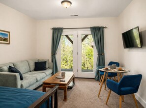 A cozy room with a sofa, a coffee table, a TV, and a dining area with chairs and a table.