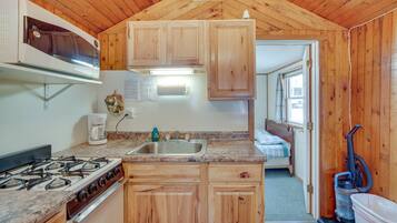 A compact kitchen with wooden cabinets, a gas stove, a sink, and a coffee maker.
