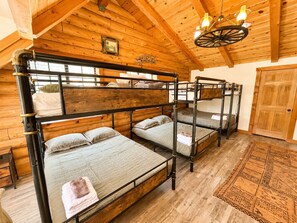 Dormitorio con literas, paredes de madera y ventilador de techo.