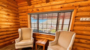 A log cabin room with two armchairs, a small wooden table, and a window with metal bars. - Bodfish Ranch/ sleeps 14 / secluded on 3.5 acres (Bodfish)