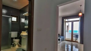 A modern bathroom with a toilet, sink, and mirror. There is a balcony with a view of the sea.