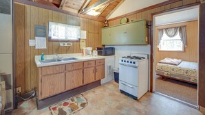 A compact kitchen with wooden cabinets, a microwave, a stove, and a sink. - Stone Lake Cabin w/ Private Deck & Fire Pit! (Stone Lake)