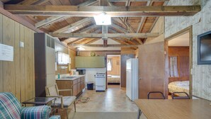 A compact, rustic room with a kitchenette, a dining area, and a bed. - Stone Lake Cabin w/ Private Deck & Fire Pit! (Stone Lake)