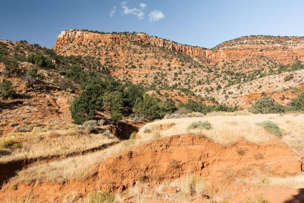 A rugged landscape with a prominent red rock formation and sparse vegetation.