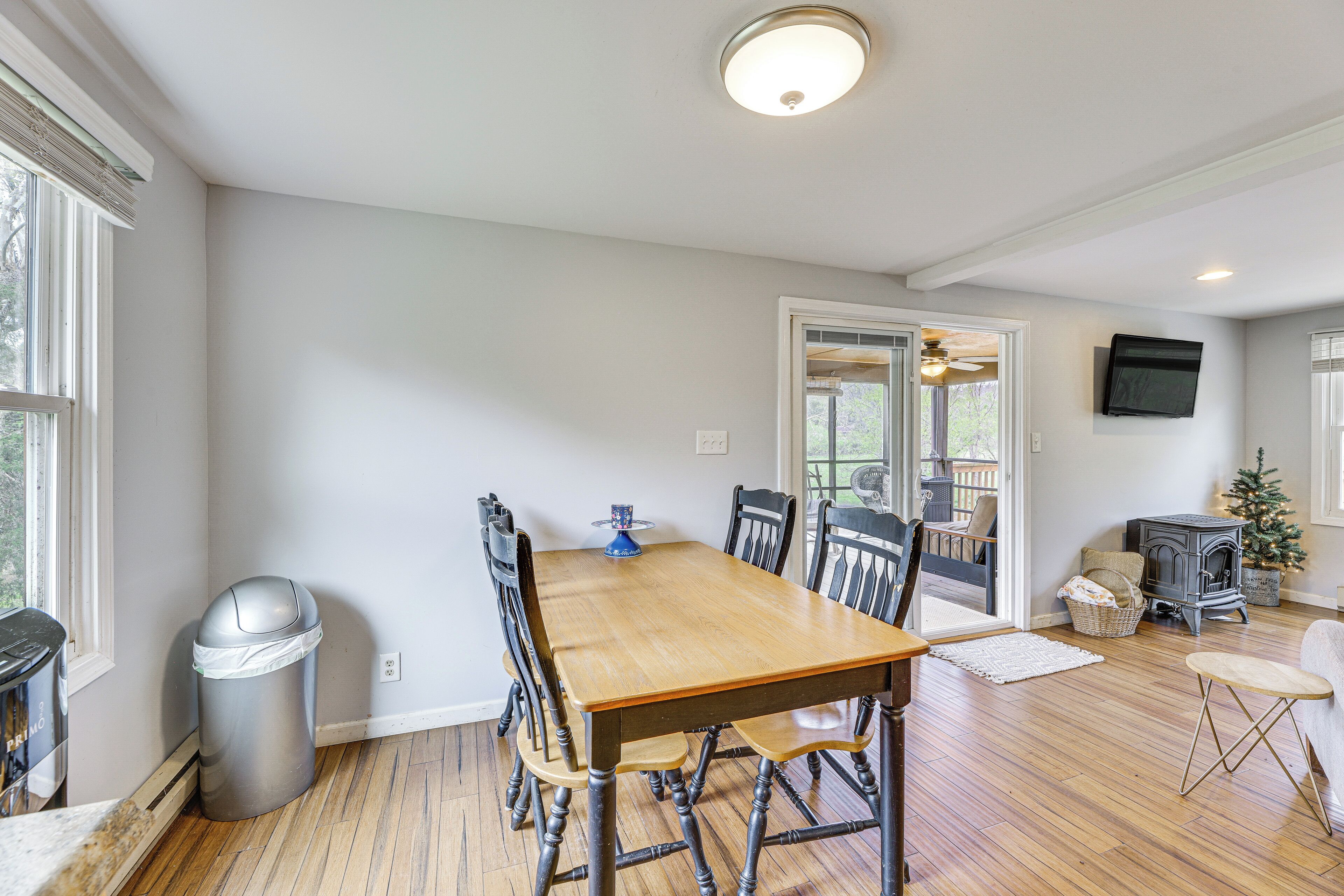A dining area with a wooden table and chairs, a trash can, and a fireplace.