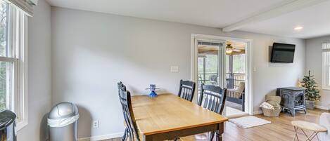 A dining area with a wooden table and chairs, a trash can, and a fireplace.