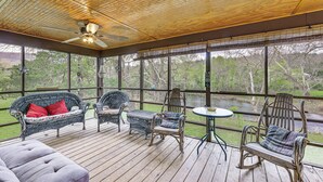 Eine überdachte Terrasse mit Korbmöbeln, einem Deckenventilator und Blick auf eine natürliche Landschaft.