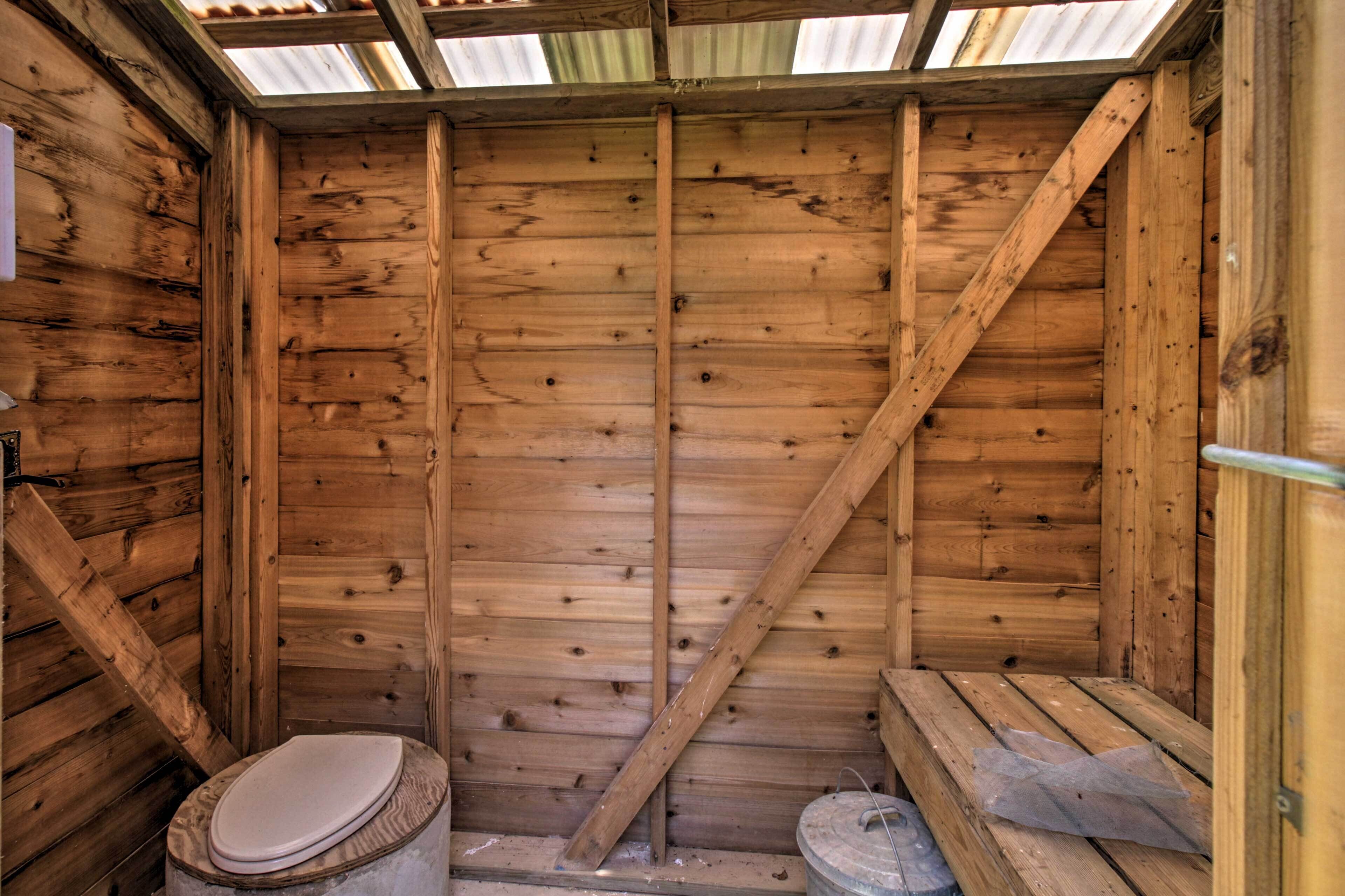 A wooden cabin with a single toilet and a bench.