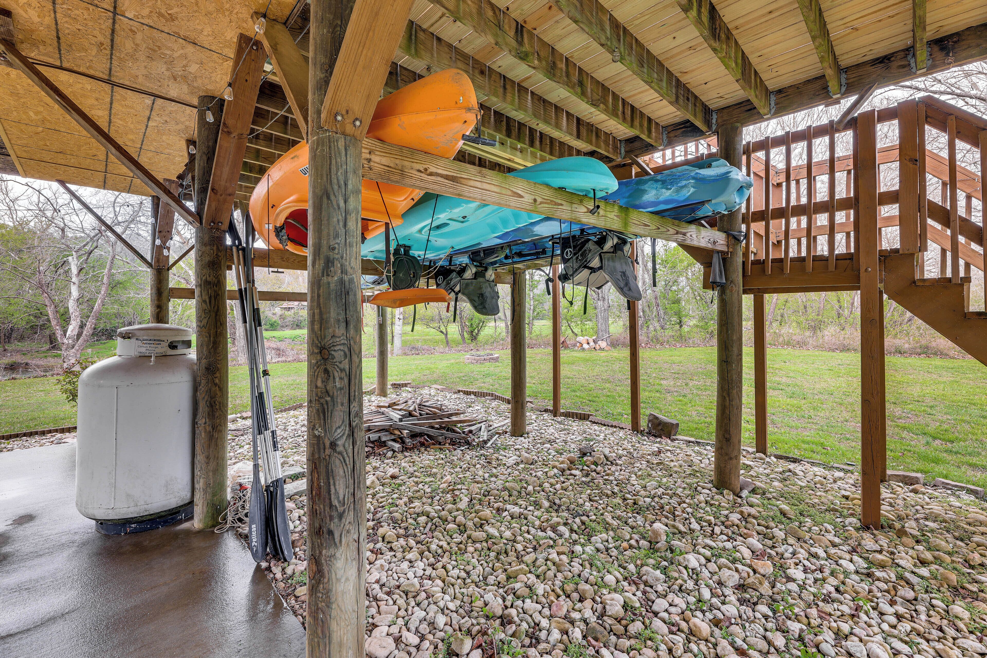 A covered outdoor area with kayaks and a propane tank.