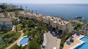 Un hotel costero con varios balcones, una piscina y vistas al mar.