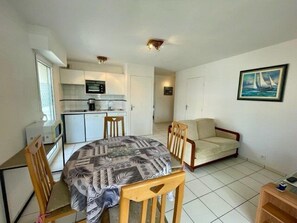 Um espaço compacto com cozinha americana, uma área de jantar com toalha de mesa estampada e um sofá.
