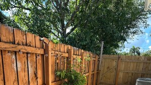 Una cerca de madera, un camino de grava y plantas en macetas.