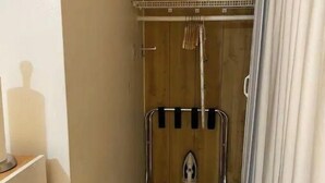 Un espacio de ducha estrecho con una puerta de madera, un perchero metálico y un perchero para toallas.