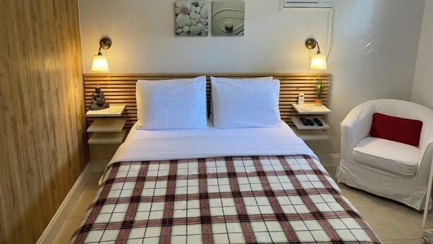 Una habitación de hotel con una cama, dos mesitas de noche, una silla y decoración en la pared.