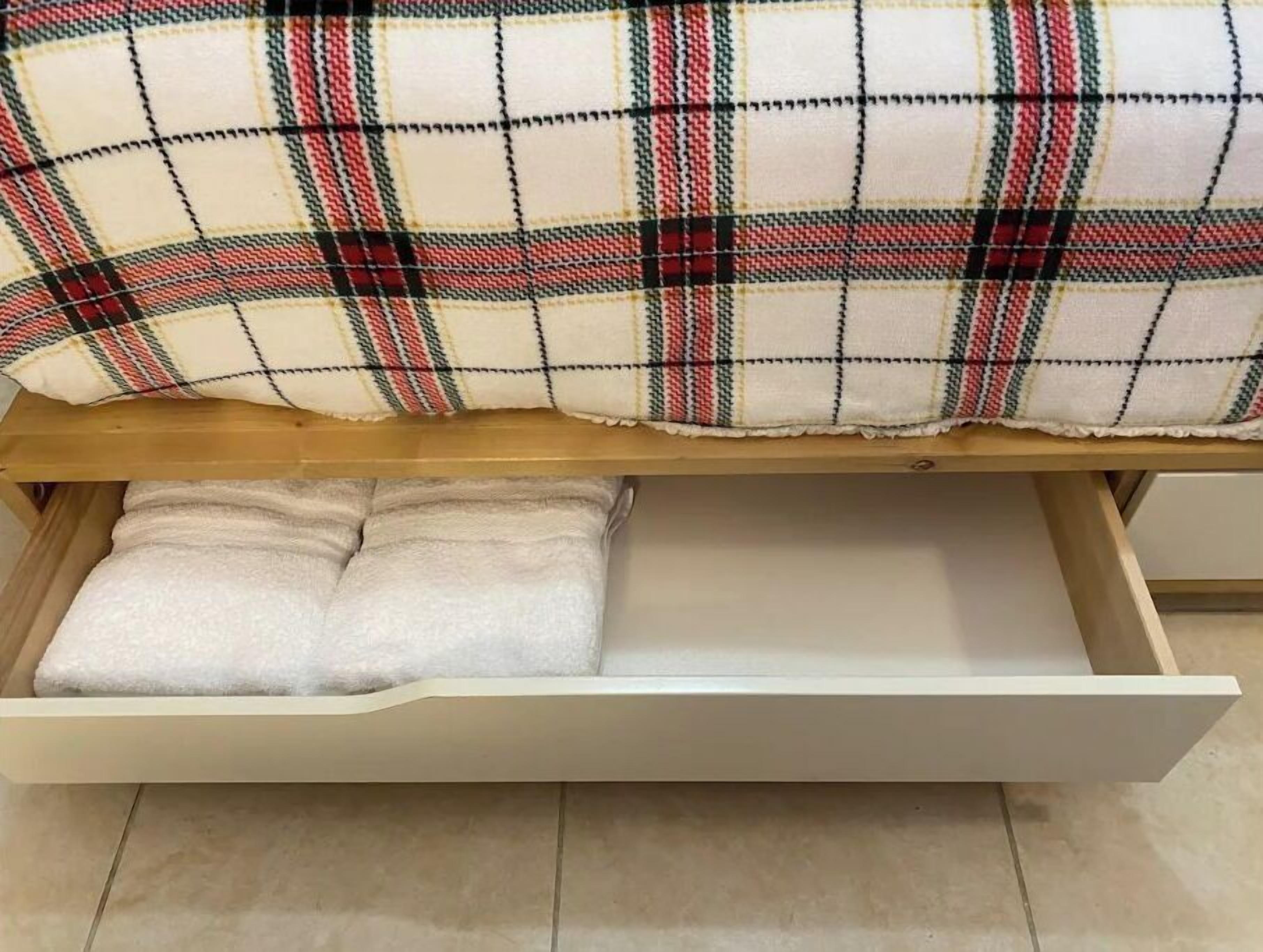 A bed with a plaid blanket and a white pillow under a wooden headboard.