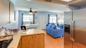 A modern kitchen with a wooden island, a blue sofa, and a stainless steel refrigerator. - Idyllic Fort Pierce Retreat - Walk to Beach! (Fort Pierce)