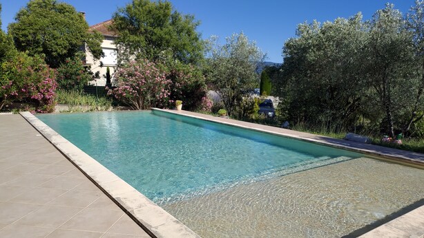 A rectangular swimming pool with clear blue water, surrounded by a tiled deck.