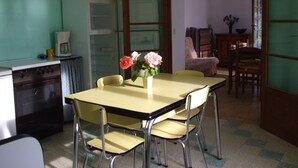 A dining area with a table and chairs, a refrigerator, and a coffee maker.