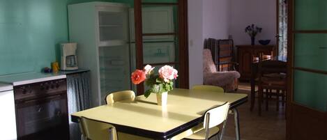 Un'area pranzo con tavolo e sedie, un frigorifero e una macchina per il caffè.