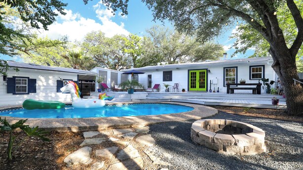 Un patio trasero con piscina, una chimenea y una casa con puerta verde.