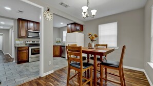 A kitchen with wooden cabinets, a dining table with chairs, and a clock on the wall.