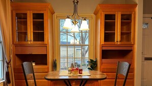 A dining area with a wooden table and chairs, a window with a view of the outside, and wooden cabinets with glass doors. - Relaxing Luxurious Waterfront in Hampton  (Hampton)