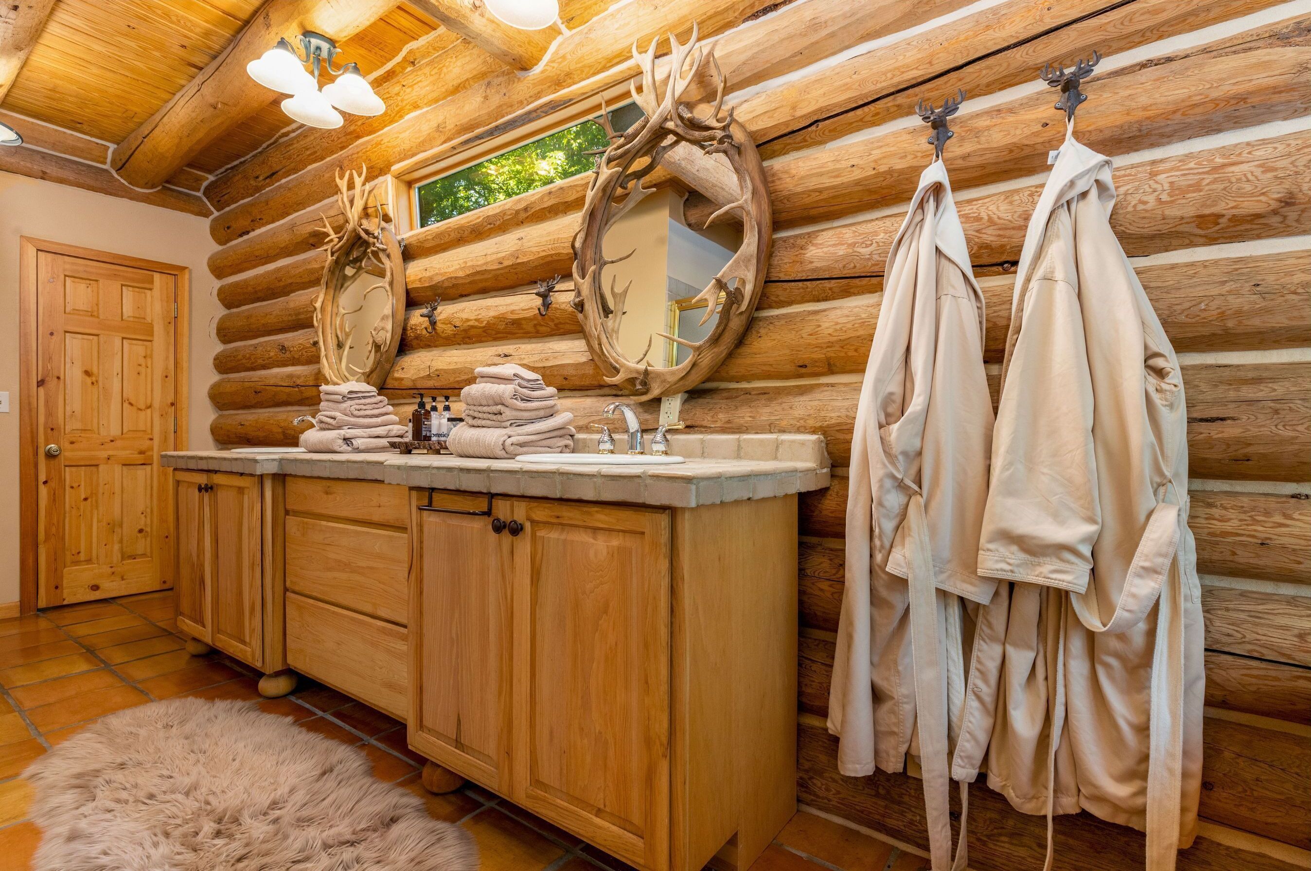 A log cabin bathroom with wooden cabinets, a sink, and a mirror.