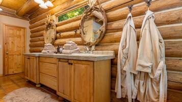 A log cabin bathroom with wooden cabinets, a sink, and a mirror.