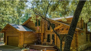 A log cabin with a front porch, a garage, and a small deck area.