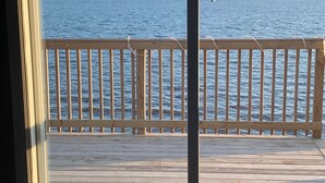 A view from a room with a large window overlooking a wooden deck and a body of water. - Newly built house located on the bay (Pace)
