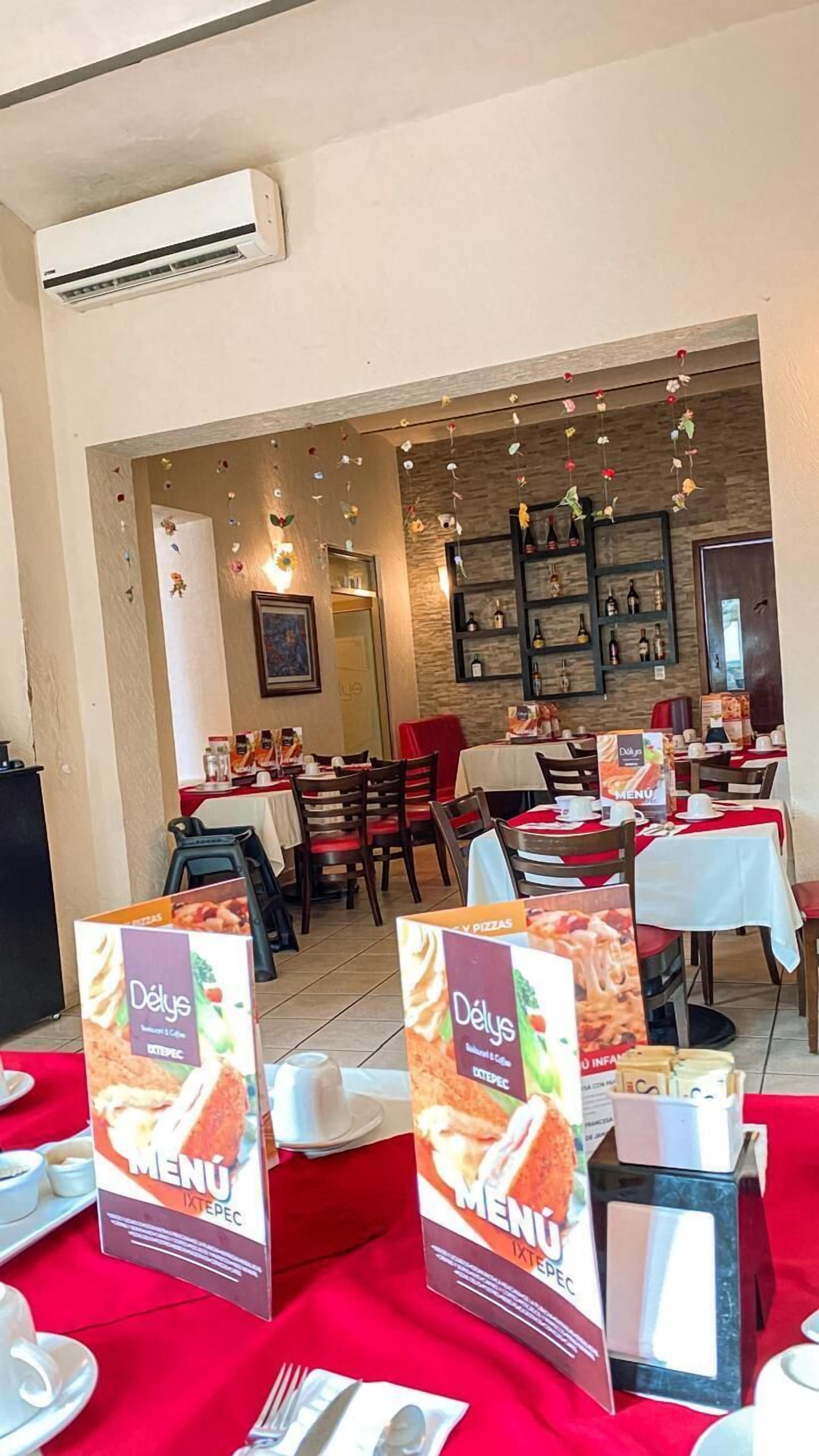 Interior de un restaurante con mesas dispuestas para comer, carteles de menú y un equipo de aire acondicionado instalado en la pared.