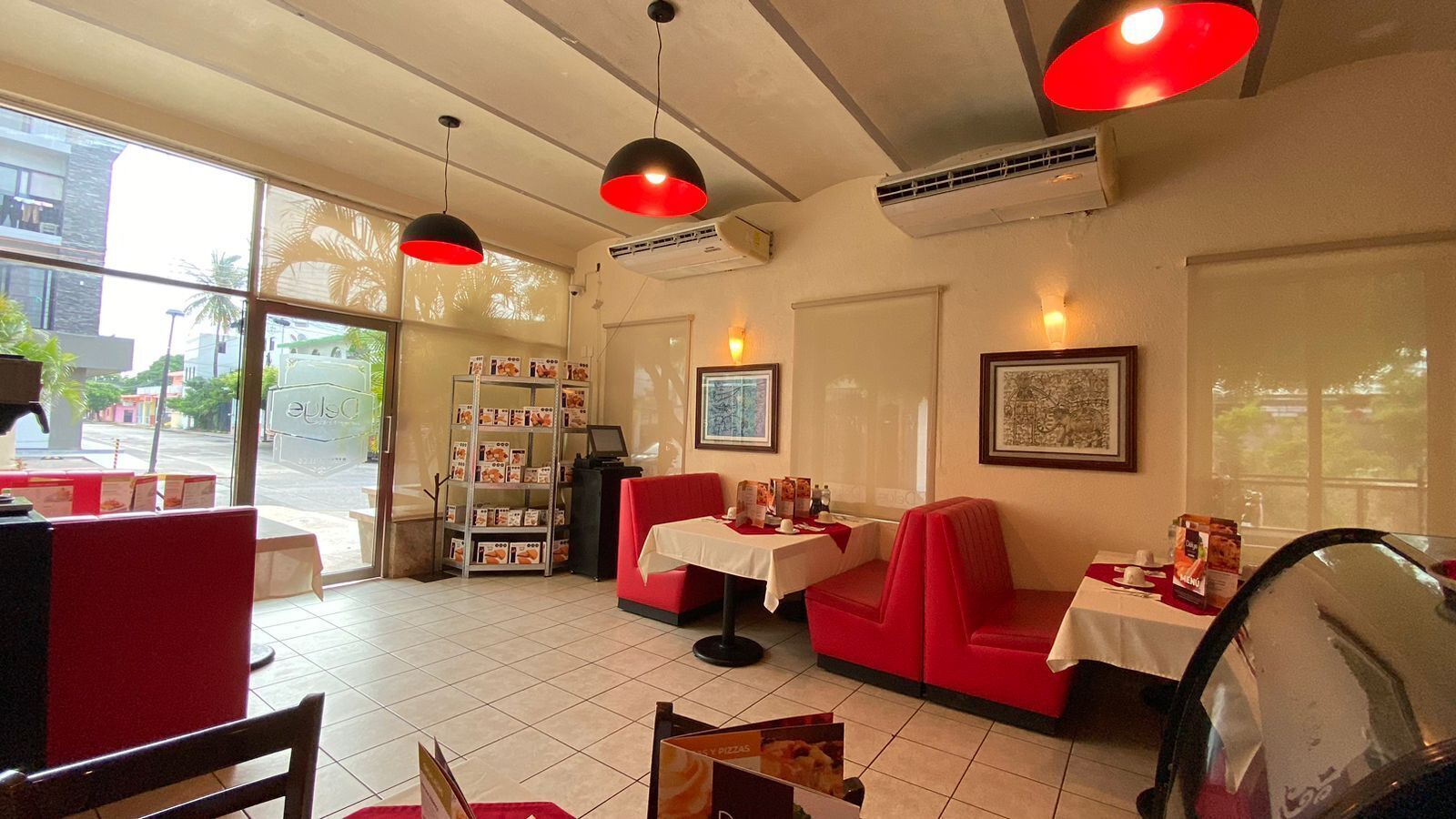 A restaurant interior with red booths, a menu stand, and pendant lighting.
