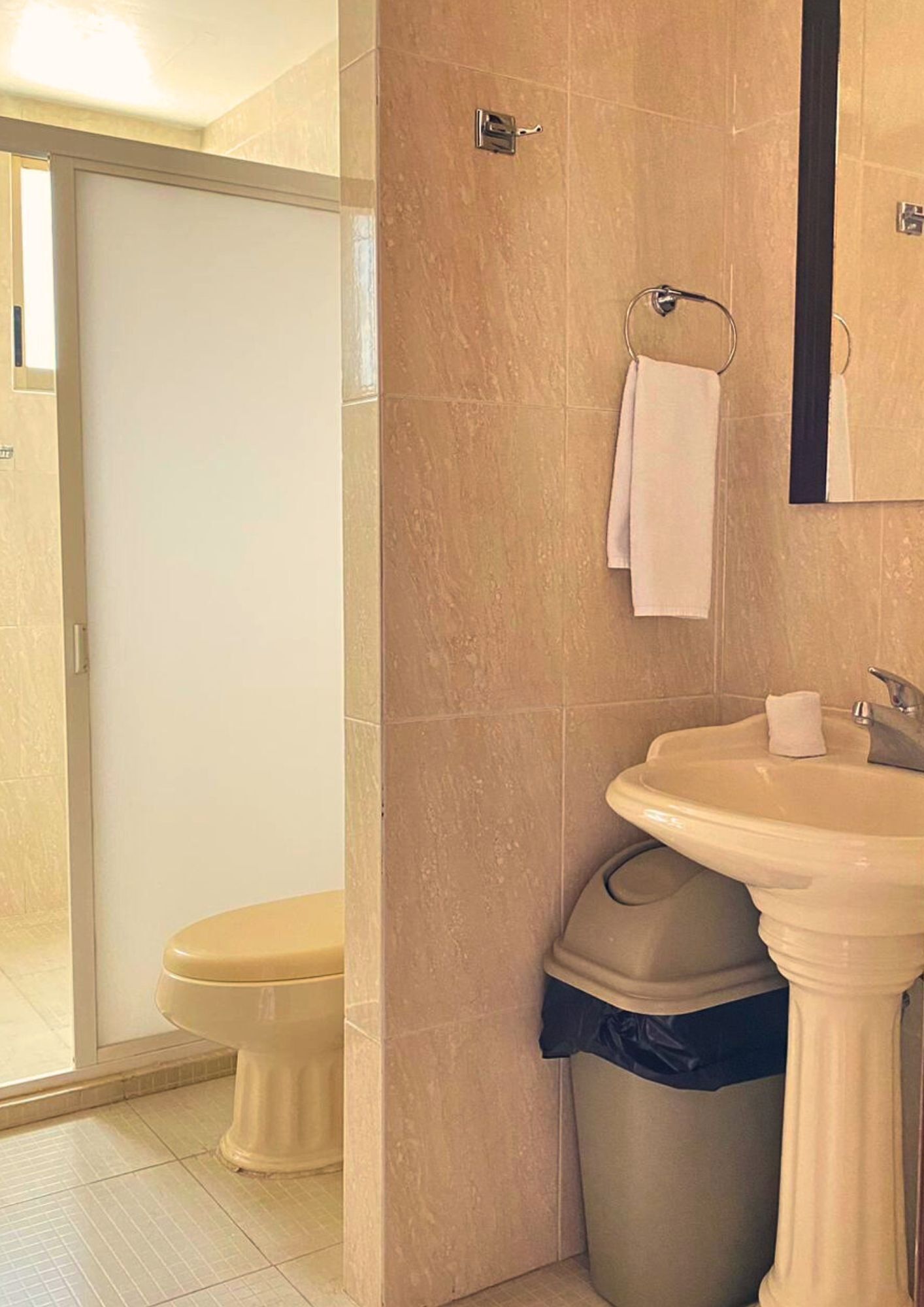 A bathroom with a toilet, sink, and trash can.
