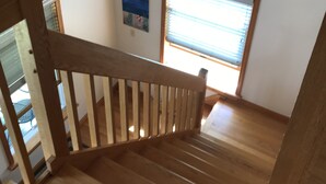 Eine Holztreppe mit Handlauf, die zu einer Empore führt.