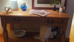 Ein Holztisch mit Lampe, gerahmten Bildern, einer Vase mit Stiften, einer Kerze und einer Schale.
