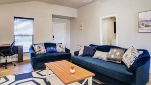Ein Wohnzimmer mit einem blauen Sofa, einem Holztisch und einem Deckenventilator.