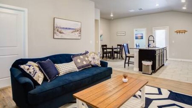 A living room with a blue sofa, a wooden coffee table, and a painting on the wall. - Milano Lodge - Cozy Retreat (Lubbock)