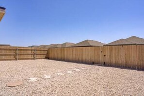 Un espace extérieur clos, doté d’un sol en gravier et d’une clôture en bois.