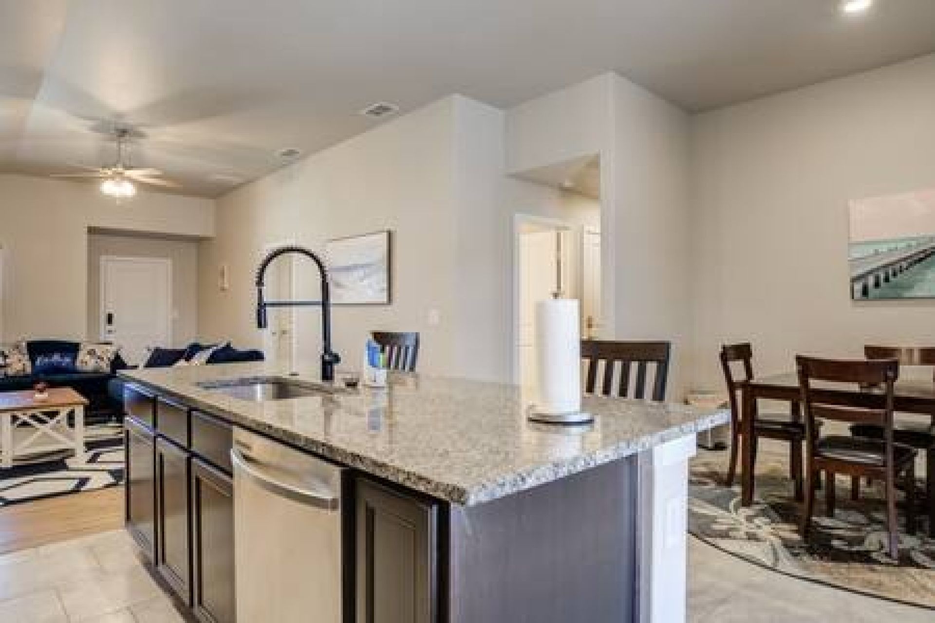 A modern kitchen with a central island, built-in appliances, and a dining area with wooden chairs.