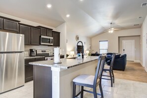 Una cocina moderna con armarios oscuros, electrodomésticos de acero inoxidable y una isla central con taburetes de bar.