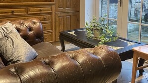 Ein Wohnzimmer mit einer Ledersofa, Holzschränken und einer Glastür, die nach draußen führt.