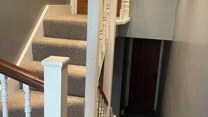 Eine Treppe mit beigefarbenem Teppich, weißen Spindeln und einem Holzgeländer.